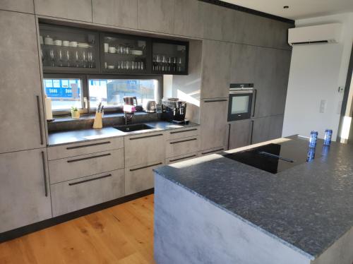 a kitchen with gray cabinets and a counter top at Luxuriöses Penthouse mit Blick auf die UNO-City und dem Kaiserwasser. 3Schlafzimmer, 2 Bäder, privat Lift ins Apartment in Vienna