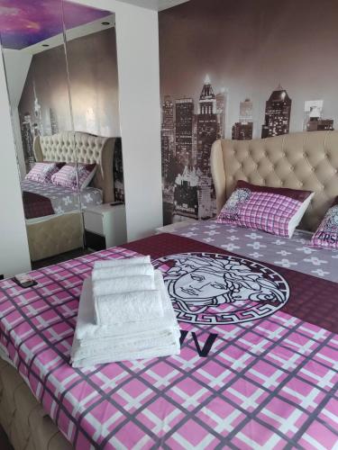 a bedroom with a large bed with a pink and purple bedspread at Hedonic Wellness Apartmani in Niš