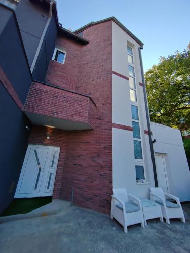 two white chairs sitting outside of a building at Hedonic Wellness Apartmani in Niš