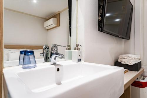 a bathroom with a white sink and a tv at WABA Classic Gwanganri in Busan