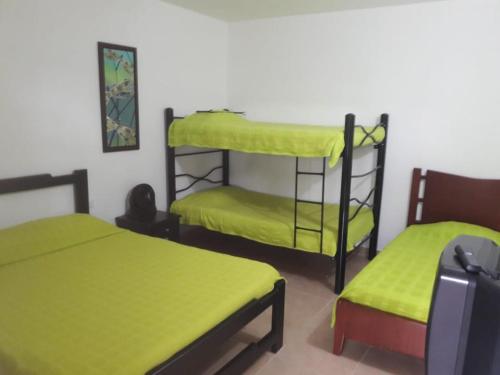 Cette chambre comprend 2 lits superposés et une valise. dans l'établissement Finca Hotel El SAMAN de alto bonito, à Montenegro