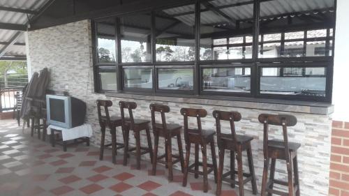 a bar with a row of chairs and a tv at Finca Hotel El SAMAN de alto bonito in Montenegro