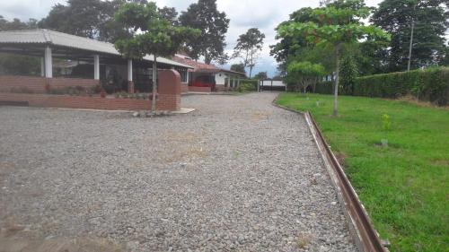 a house with a gravel driveway in front of a yard at Finca Hotel El SAMAN de alto bonito in Montenegro