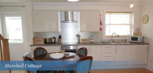 a kitchen with a table and chairs in it at Harebell Cottage in Killean