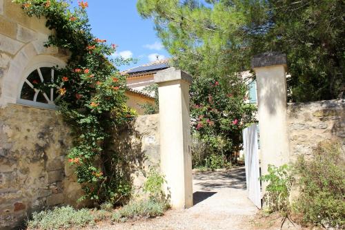 a stone fence with a gate and flowers on it at NEW! Gîtes de Charme au Mas de Soleil in Goudargues