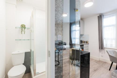 a bathroom with a toilet and a glass shower at Newly refurbished Studio in Kensal green F in London