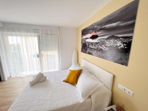 een slaapkamer met een wit bed met een foto aan de muur bij Rooms Laredo in Laredo