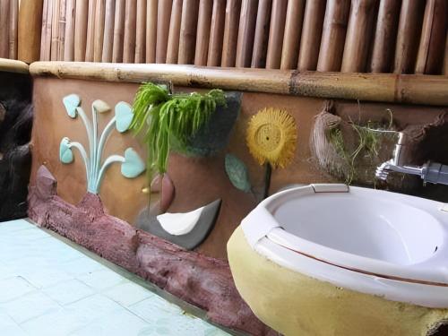 a bathroom with a toilet and a painting on the wall at back to nature ecotourism in Bukit Lawang