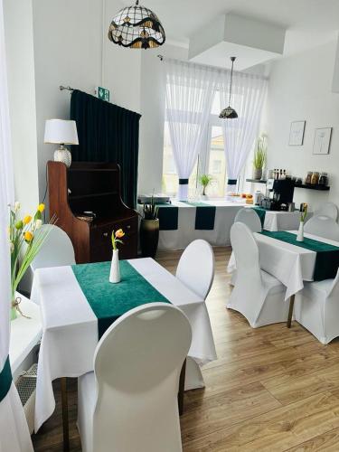 a living room with white tables and chairs and a piano at Hotel Dana in Bytów