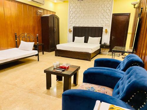 Habitación con 2 camas, sillas azules y mesa. en HOTEL ROYAL ONE en Multán