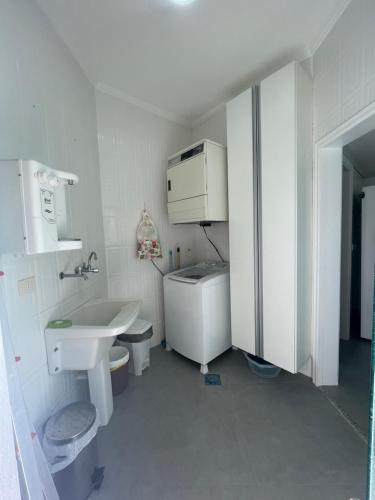 a white bathroom with a sink and a toilet at Casa ideal no Guaruja in Guarujá