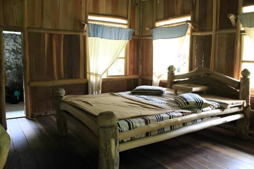 a bed in a room with wooden walls and windows at back to nature ecotourism in Bukit Lawang