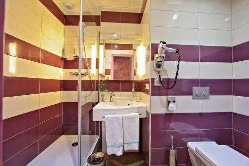 a bathroom with a sink and a shower at The Originals City - Hôtel Saint-Martial, Limoges Centre in Limoges