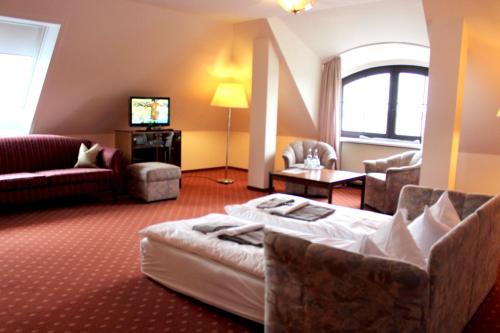 um quarto de hotel com uma cama, um sofá e uma televisão em Hotel Seerose Bad Malente em Malente