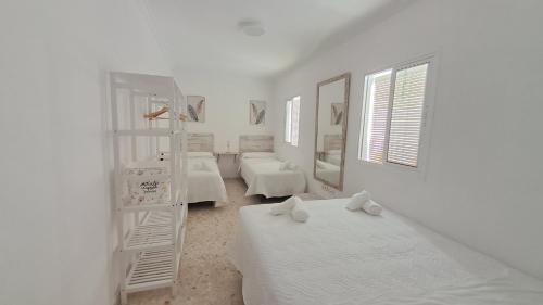 Habitación blanca con 2 camas y escalera en Apartamentos TrianaSol en Sevilla