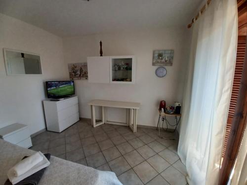 een woonkamer met een tafel en een televisie bij CASA SIBILLA bi-locale con terrazza a 60 metri dal mare in Marinella
