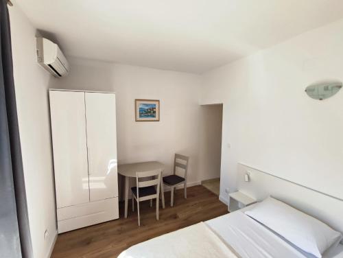 ein Schlafzimmer mit einem kleinen Tisch und einem weißen Schrank in der Unterkunft Apartmani Seka in Vodice