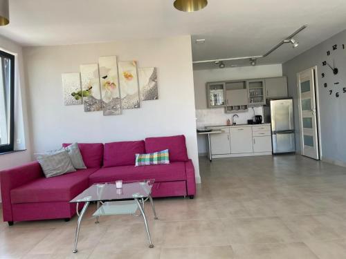 a living room with a purple couch and a kitchen at Apartament III w Centrum - Winda - 50 metrów od Starego Rynku in Kościerzyna