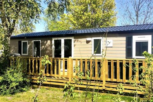 a small house with a wooden deck in a yard at Modern holiday Chalet on lake side holiday park in Lauwersoog