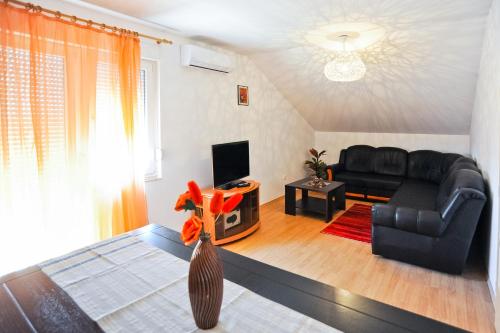 sala de estar con sofá negro y TV en Apartmani Roko, en Zadar