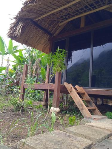 a wooden bench under an umbrella in front of a house at Ngoặng homestay - phòng nghỉ trọ in Chiêm Hóa