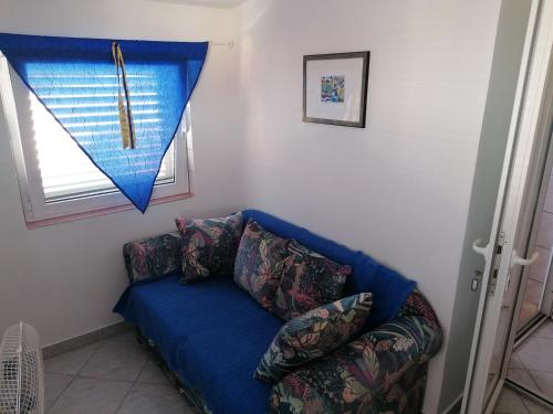 niebieską kanapę w pokoju z oknem w obiekcie Apartmani Marija i Josip w mieście Vir