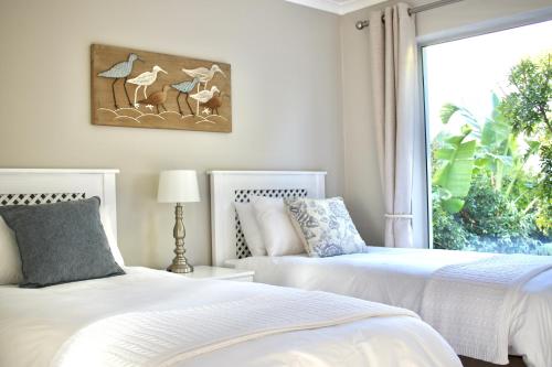 a bedroom with two beds and a window with birds at Ocean Pearl Hermanus - 5 Bedrooms in Hermanus