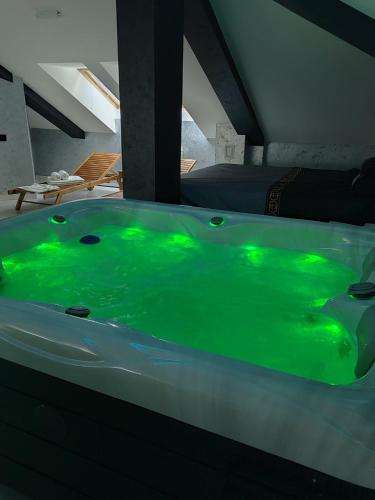 a green bath tub in a room with a bed at Hedonic Wellness Apartmani in Niš