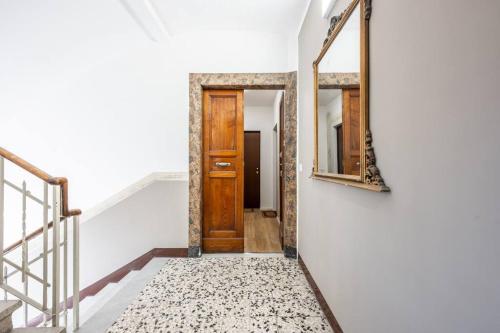 a hallway with a wooden door and a mirror at Cucchiari Suite 1A in Modena