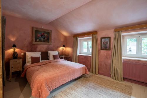 a bedroom with a bed and two windows at La Chambre Rose in Durbuy