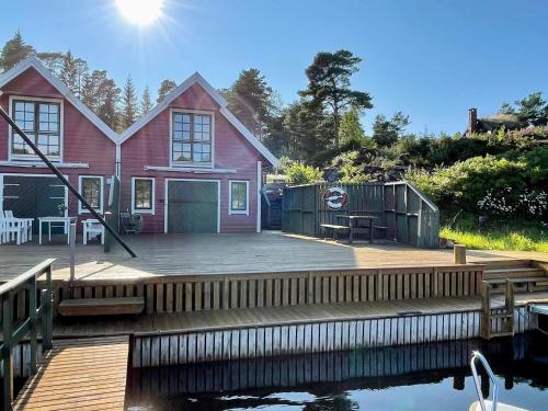 a red house with a dock next to the water at Holiday home MOSTERHAMN V in Mosterhamn