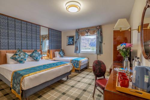 a hotel room with two beds and a desk at Muthu Fort William Hotel in Fort William