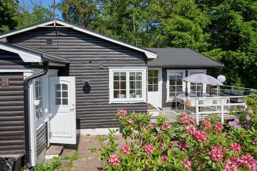 a small cabin with a porch and a white door at Peaceful getaway in the woods w/ fireplace in Åsljunga
