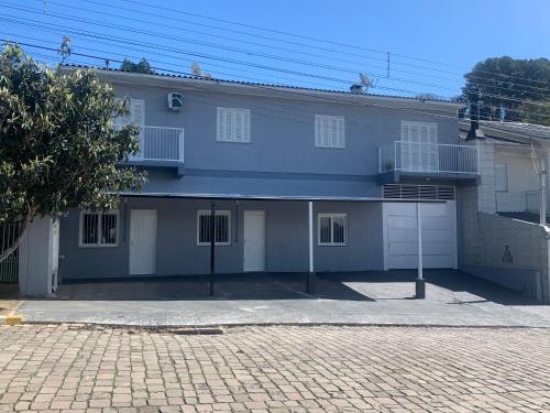 a house with two garage doors and a brick driveway at Apartamento Aconchegante e Silencioso em Bairro Tranquilo in Bento Gonçalves