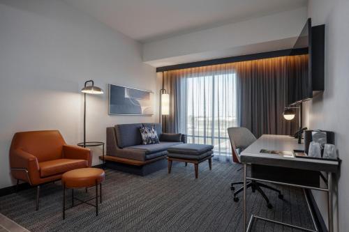 a living room with a couch chair and a desk at Courtyard by Marriott Indianapolis Fishers in Fishers