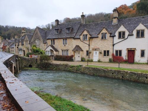 un río en un pueblo con casas y un puente en The Delkin Shepherds Huts Castle Combe, en Castle Combe