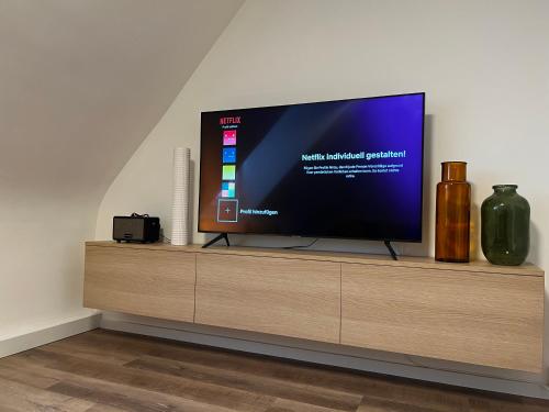 ガッゲナウにあるCity-Designapartmentの木製エンターテイメントセンターに座って薄型テレビを視聴できます。