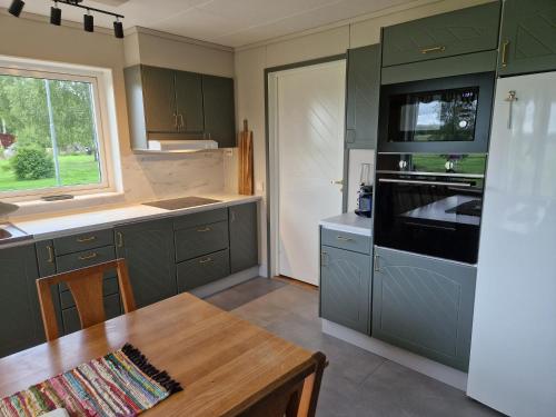Lantlig villa utanför Uppsala في Alunda: مطبخ مع دواليب خضراء وطاولة خشبية