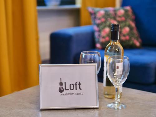 a bottle of wine and two glasses on a table at Loft Apartments Gliwice in Gliwice