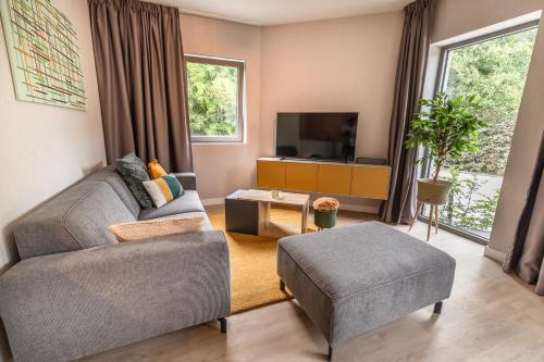 a living room with a couch and a tv at Abalona Hotel & Apartments in Dendermonde