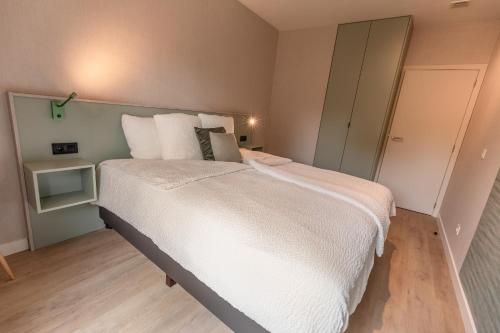 a bedroom with a large bed with white sheets and pillows at Abalona Hotel & Apartments in Dendermonde