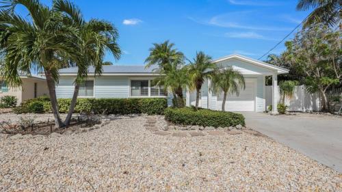 una casa blanca con palmeras delante en Gladiolus On The Water Home, en Anna Maria