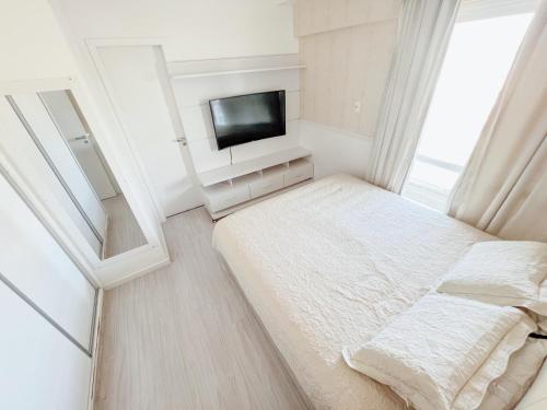 a small bedroom with a bed and a tv at Apartamento de frente para o Mar in Vitória