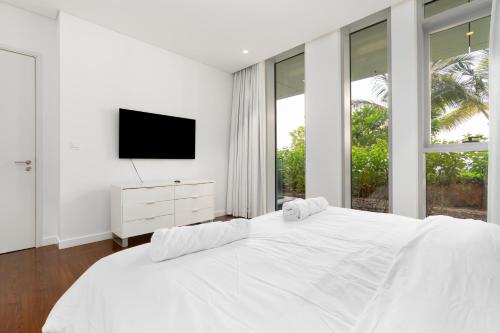 a white bedroom with a large bed and a tv at Brand new 1 BHK in Bluewaters in Dubai