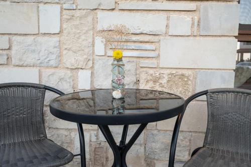 a glass table with two chairs and a vase on it at Perion stone apartment sea front in Kolymvari