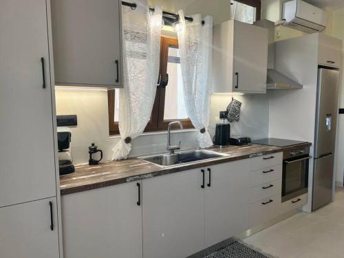 a kitchen with white cabinets and a sink and a window at Perion stone apartment sea front in Kolymvari