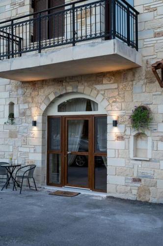 a building with a balcony and a door with a table at Perion stone apartment sea front in Kolymvari
