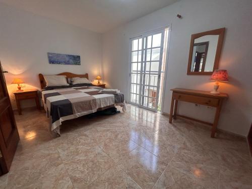 1 Schlafzimmer mit einem Bett, 2 Tischen und einem Spiegel in der Unterkunft Alquilaencanarias Llano del Camello in San Miguel de Abona
