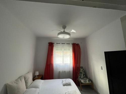 ein Schlafzimmer mit einem Bett und einem Fenster mit einem roten Vorhang in der Unterkunft Piso completo a 5 minutos del metro linea 5 verde in Madrid