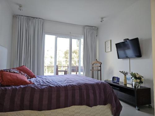 a bedroom with a bed and a tv and a window at Green Park penthouse 2 dormitorios in Punta del Este
